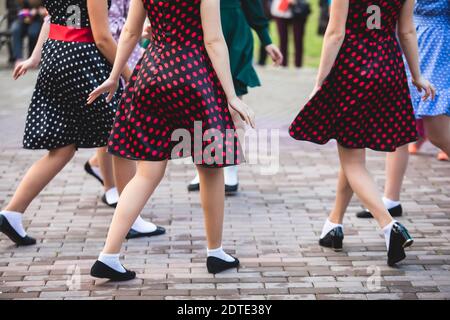 Mujeres con vestidos de punto polka vintage bailando en el parque de la ciudad, vista de cerca de los mismos de baile negro calcetines swing femenino de jazz