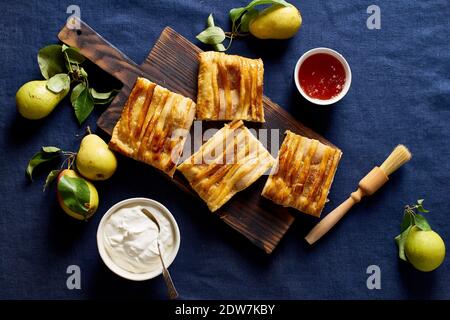 Dartois en rodajas con peras - tarta de hojaldre francesa con frutas y frangipane sobre fondo azul oscuro Foto de stock