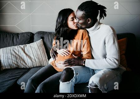 Un joven romántico besando a una mujer embarazada en casa