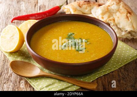 Sopa de lentejas rojas asiáticas y puré de verduras servida con primer plano de pan y limón en un Bol sobre la mesa. Horizontal Foto de stock