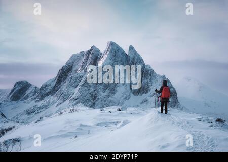 Mujer montañesa de pie en la cima del pico de Segla con majestuoso Montaña nevada en invierno en la isla Senja Foto de stock