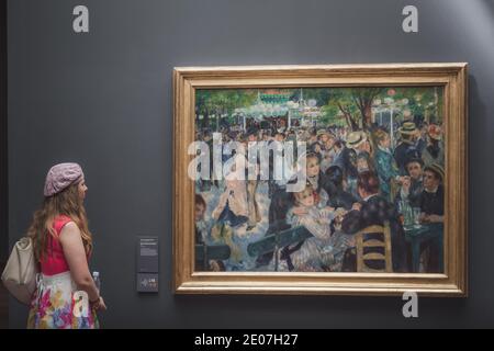 París, Francia - 22 de agosto de 2015: Un visitante al Musee d'Orsay mirando la famosa obra maestra de Renoir 'Bal du moulin de la Galette' Foto de stock