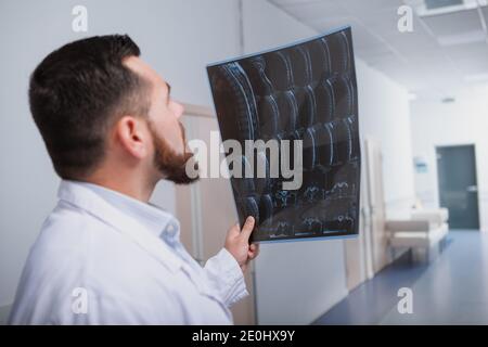 Vista posterior de un médico masculino que se concentra, examinando la resonancia magnética del paciente Foto de stock