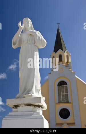 Una estatua de Jesús se encuentra frente a la histórica y colorida Iglesia Católica de Santa Ana, Noord, Aruba.