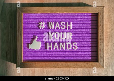 Lávese las manos hashtag mensaje en la cartelera púrpura aviso en la tienda de negocios buena higiene de las manos para la prevención del coronavirus. Señal de fieltro para las redes sociales Foto de stock