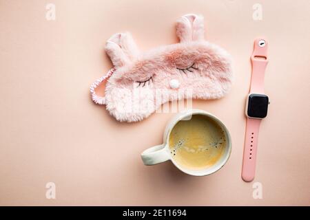 máscara para dormir y taza de café sobre fondo rosa. El concepto de comenzar un nuevo día, Buenos días o terminar el día, tarde por la noche.