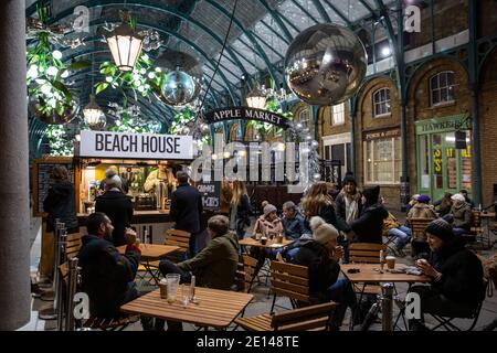 Los compradores de Navidad se sientan y se llevan un café socialmente distanciado en la Covent Garden Piazza durante el Tier2 Coronavirus Lockdown Measures, Londres, Reino Unido Foto de stock