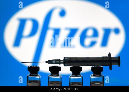 Moscú - 5 de enero de 2021: Concepto de vacuna Pfizer COVID-19. Jeringa y botellas con vacuna de EE.UU. Para coronavirus en el fondo del logotipo. Droga del virus de la corona, lesión