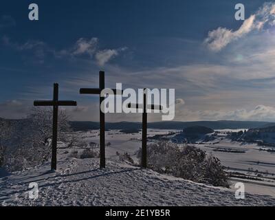 Tres cruces cristianas en la cima de la colina de Kornbühl cerca de Burladingen, Alemania en la sierra baja Alb Suabia con hermoso paisaje invernal. Foto de stock