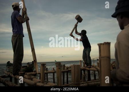 Hombres construyendo una estructura costera utilizando postes de bambú en la aldea de Cilincing, en la zona costera de Yakarta, Indonesia. Foto de archivo (2008). Foto de stock