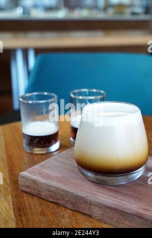 Primer plano taza de vidrio de Nitro café de preparación fría sobre mesa de bandeja de madera, café negro lentamente infundiendo con gas nitrógeno