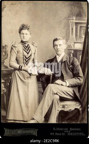 Retrato victoriano de una joven pareja de moda que ha recibido una carta importante que parece ser una buena noticia. Tomado c1897 en Bristol por H Willetts