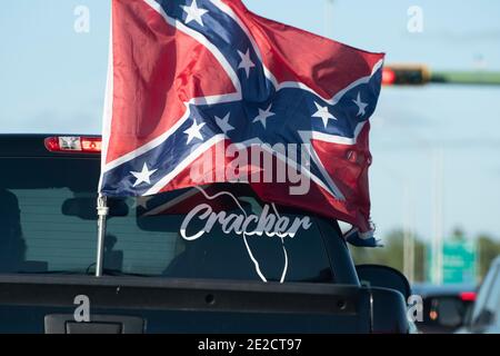 Lo que se considera una bandera rebelde vuela detrás de un camión mostrando que el conductor es un Cracker de Florida, como se indica en una etiqueta en la parte trasera del camión. Foto de stock