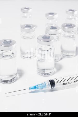 Viales de vacuna COVID-19 y jeringa sobre fondo blanco Foto de stock