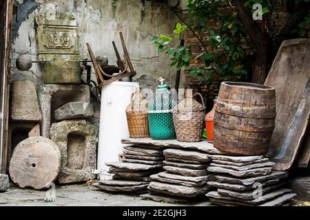 Una selección de demijons de mimbre de época, las losas de pavimentación antiguas reclamadas, barril de vino de madera para la venta en un patio de recuperación en el casco antiguo de Plovdiv, Bulgaria Foto de stock
