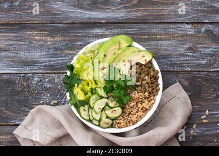 Green Buddha Bowl con lentejas, quinoa, aguacate, pepino, lechuga fresca, hierbas y semillas. Deliciosa alimentación sana y equilibrada. Sobre un fondo de madera, Foto de stock