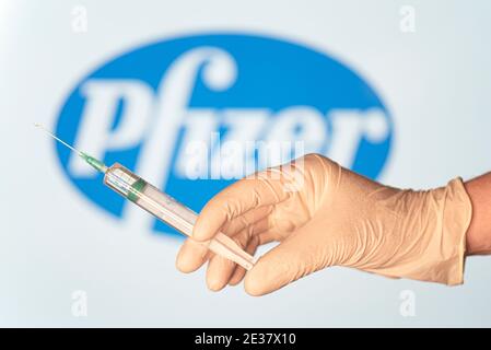BERLÍN - ENERO 17: Concepto de imagen. La vacuna contra el coronavirus por Pfizer, la mano del médico con jeringa y la vacuna contra el logotipo de Pfizer en Berlín, Janu Foto de stock