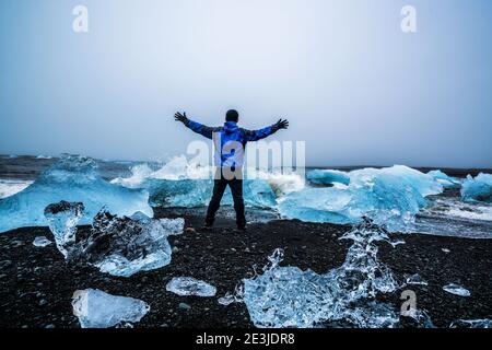 Un viajero joven viaja a Diamond Beach en Islandia. Hielo congelado en la playa de arena negra conocido fluye de Jokulsarlon hermosa laguna glaciar en Foto de stock