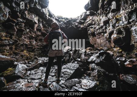 Mujer viajero explorar túnel de lava en Islandia. Raufarholshellir es un hermoso mundo escondido de cueva. Es una de las lava más largas y más conocidas