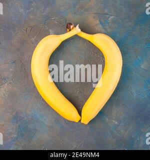 Dos plátanos amarillos están dispuestos en forma de corazón. El concepto del día de San Valentín. Primer plano Foto de stock
