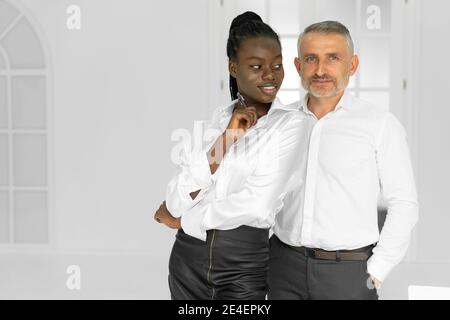 Empresario enérgico coqueteando con un joven secretario africano en el lugar de trabajo