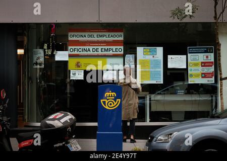 Madrid, España; septiembre de 19 2020: Mujer delante de una oficina de empleo (SEPE) leyendo los carteles que se muestran en la ventana Foto de stock