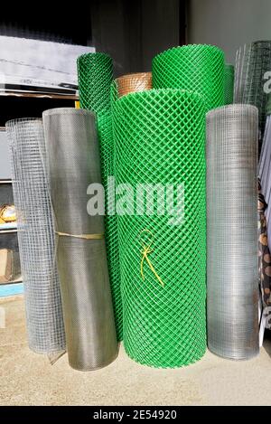 Matriz de rollos de metal y plástico verde de malla de alambre utilizada en la industria de la construcción para la venta en una ferretería en Filipinas, Asia Foto de stock