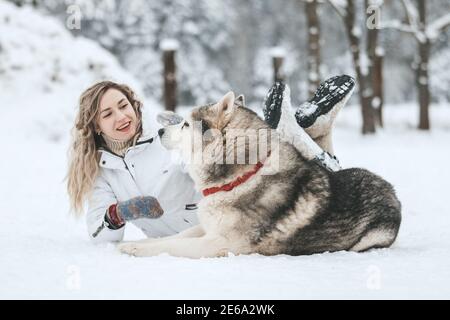 La chica se monta en un trineo en un trineo con huskies siberianos en el bosque de invierno. Mascota. Husky. Cartel artístico de Husky, impresión de Husky,
