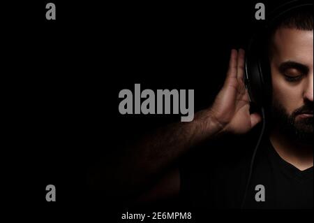 Formato Billboard. Día Internacional de DJ. Retrato de músico barbudo en auriculares sobre fondo negro aislado Foto de stock