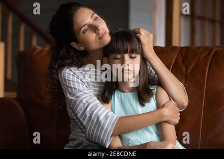 De cerca la madre cariñosa abrazando, calmando a la hija pequeña disgustada