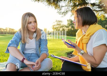 Conversación de la joven con psicólogo, trabajador social, al aire libre en la reunión en el parque en el césped Foto de stock