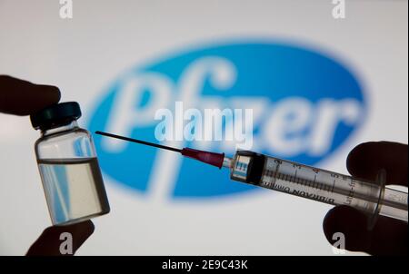 OXFORD, Reino Unido - Febrero de 2020: Una jeringa de vacuna covid delante del logotipo de pfizer Foto de stock