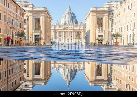 Las frecuentes duchas de lluvia crean piscinas en las que el maravilloso casco antiguo de Roma se refleja como en un espejo. Aquí en particular la Basílica de San Pedro Foto de stock