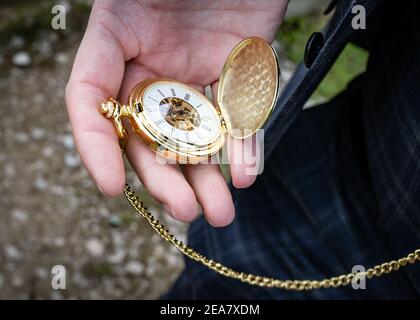 Reloj de bolsillo dorado con cadena abierta en la mano para comprobar tiempo al aire libre sostenido por el hombre que lleva traje Fotografía de stock Alamy