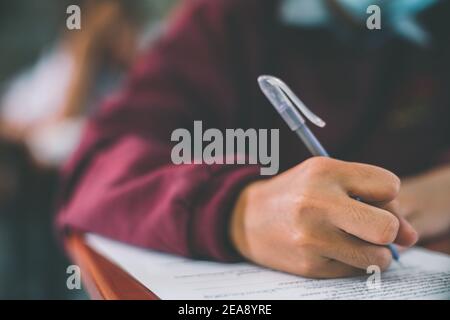 La mano del estudiante está tomando el examen y escribiendo la respuesta concepto de prueba de aula para educación Foto de stock