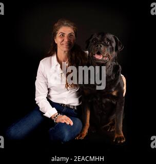 purebred rottweiler y mujer delante de fondo negro