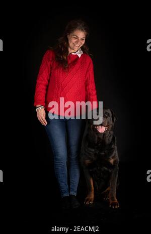 purebred rottweiler y mujer delante de fondo negro