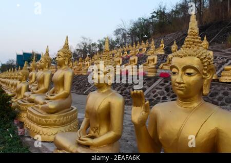 Muchas estatuas de Buda de Oro en una fila al aire libre en el templo en la colina. Estatuas de Buda sentado en Wat Phu Salao en la colina cerca de Pakse, Laos. Buda sta Foto de stock