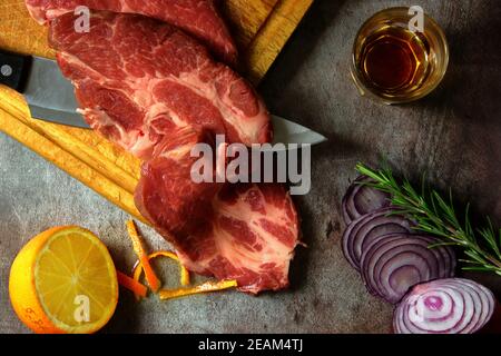 lomo de titolopork de senza se pone sobre una tabla de cortar, composición con cebolla, romero, naranja y brandy para la salsa Foto de stock