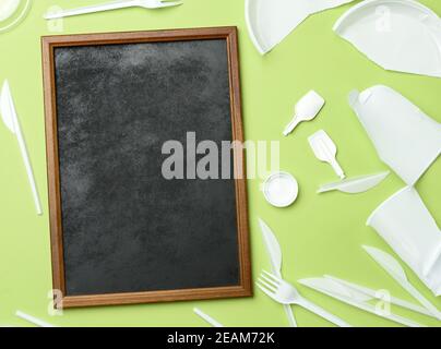 marco de madera vacío y vajilla de plástico blanco roto en verde antecedentes Foto de stock