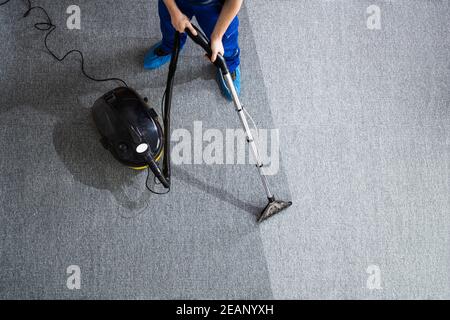 Hombre limpiar con aspiradora piso mientras la mujer acostada con