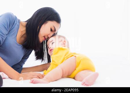 madre besando a su bebé recién nacido en una cama blanca Foto de stock