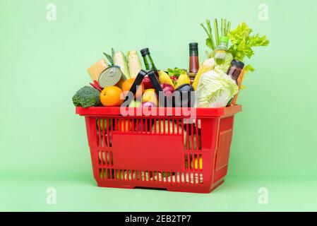 Comida colorida y comestibles incluyendo frutas frescas y verduras en cesta de plástico del supermercado rojo Foto de stock