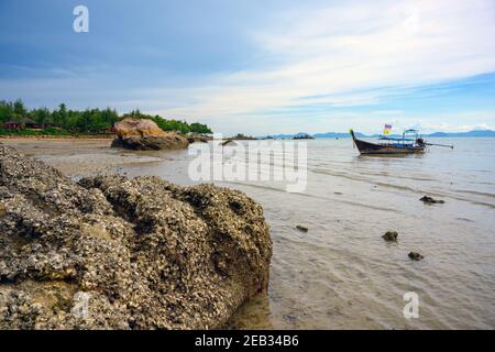 Un barco turístico está amarrado en el agua por la playa en Tup Kaek, Krabi, Tailandia durante el día con un hermoso cielo. Foto de stock