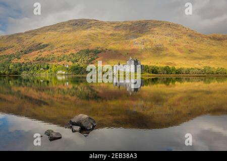 Kilchurn castillo en Escocia. Con vistas al lago AWE, el castillo se refleja perfectamente en el agua. Colores otoñales en las colinas detrás Foto de stock