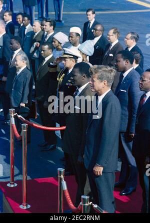 Ceremonia de llegada de Ahmed Su00e9kou Touru00e9, Presidente de Guinea, 11:00AM. Ceremonias de llegada para el Presidente de Guinea, Ahmed Su00e9kou Touru00e9. De pie en la plataforma de revisión en primer plano (L-R): Presidente Touru00e9; Presidente John F. Kennedy; Ministro de Relaciones Exteriores de Guinea, Louis Lansana Bu00e9avogui; Embajador de Guinea, Dr. Seydou Conte (parcialmente oculto en el borde del marco). También en la foto: Aide Naval al Presidente Kennedy, Capitán Tazewell T. Shepard, Jr.; Embajador de Vietnam, Tran Van Chuong; intérprete del Departamento de Estado de Estados Unidos, Josu00E9 de Seabra. Transporte aéreo militar S