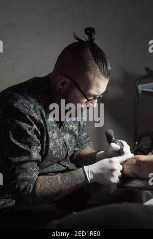 Tatuaje usando máquina y haciendo tatuajes con tinta negra salón en cliente  anónimo recortado Fotografía de stock - Alamy