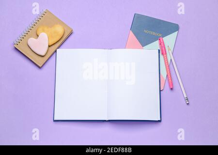 Libro abierto en blanco, cookies y cuaderno sobre fondo de color Foto de stock