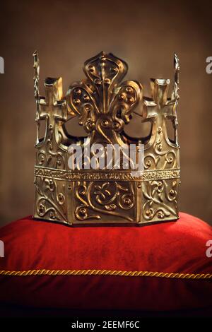 Corona de oro del Rey colocada en un cojín de terciopelo rojo. La imagen se puede utilizar para novelas, libros históricos que cuentan la vida de un rey. Foto de stock