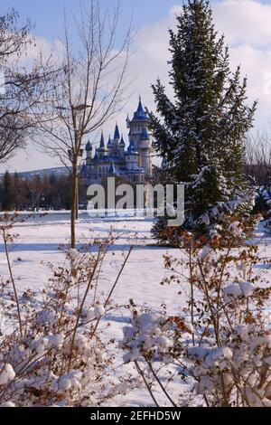 Retro castillo azul detrás de los árboles bajo la nieve en invierno Foto de stock